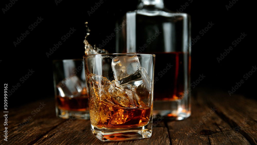Splashing whiskey from glass with ice cubes inside Splashing whiskey from glass with ice cubes inside