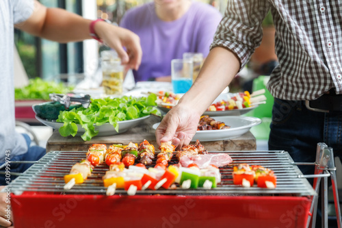A man grilling pork and barbecue in dinner party. Food  people and family time concept.