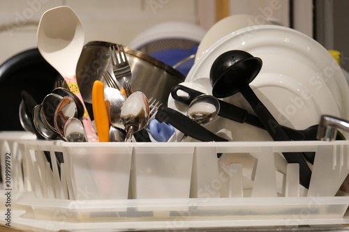 Plates, cups, forks and ladles placed on a kitchen tray.
