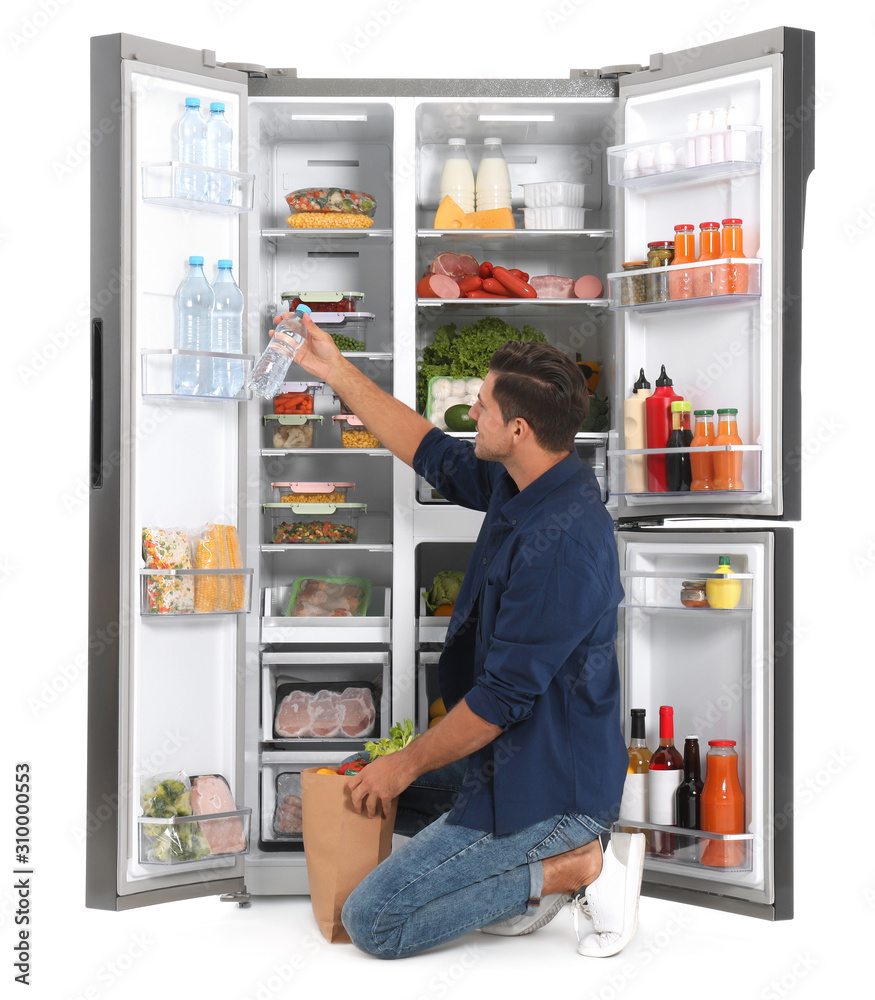 Man with bag of groceries near open refrigerator on white background Man with bag of groceries near open refrigerator on white background