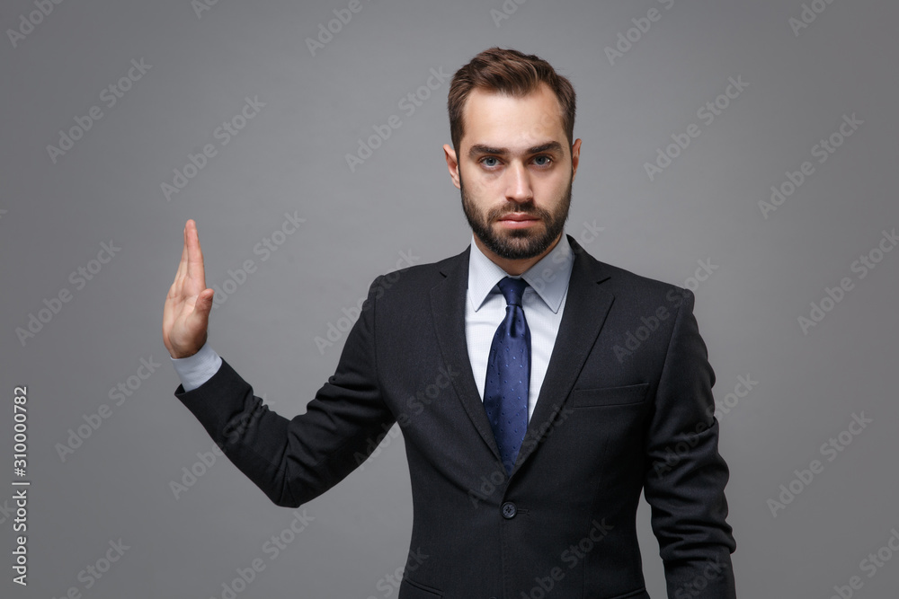 Serious young bearded business man in classic suit shirt tie posing isolated on grey background. Achievement career wealth business concept. Mock up copy space. Showing stop gesture aside with palm. Serious young bearded business man in classic suit shirt tie posing isolated on grey background. Achievement career wealth business concept. Mock up copy space. Showing stop gesture aside with palm.
