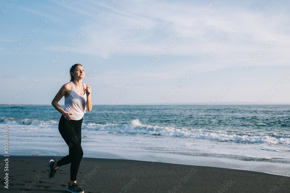 Young sportswoman jogging on sea beach
