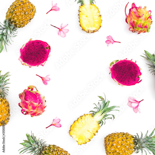 Tropical frame made of pineapple and dragon fruits with pink flowers on white background. Flat lay