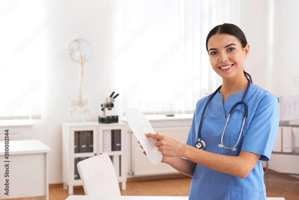 Young female orthopedist showing insole in clinic Young female orthopedist showing insole in clinic