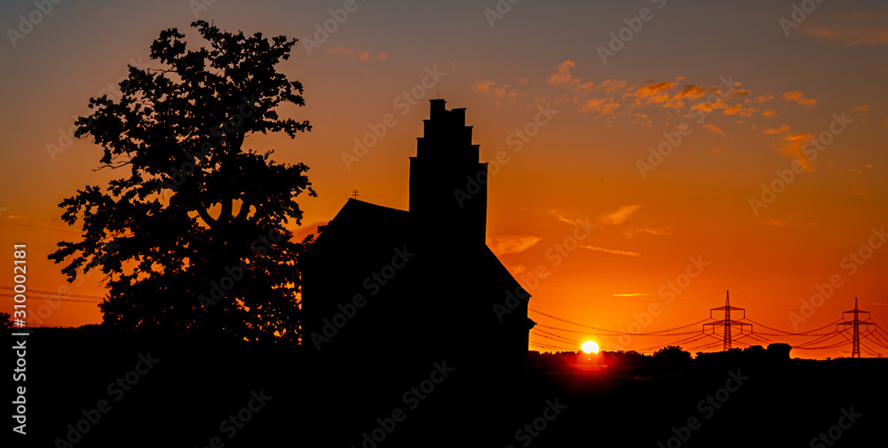 Obraz premium Beautiful sunset with a church and powerlines near Huett, Bavaria, Germany