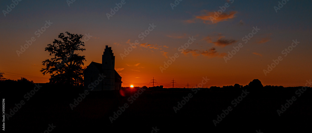 Beautiful sunset with a church and powerlines near Huett, Bavaria, Germany