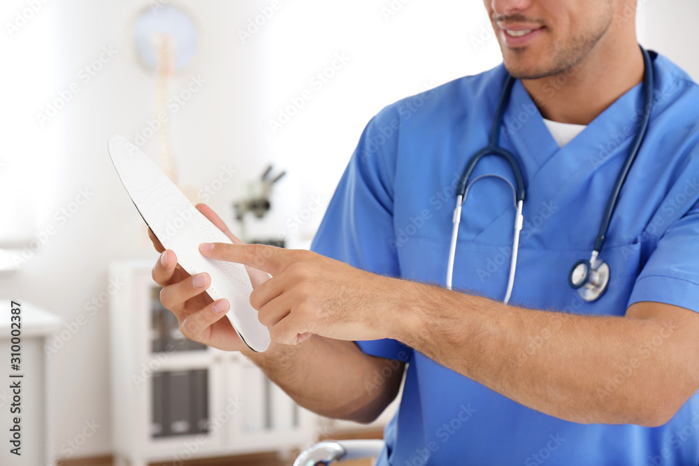Male orthopedist showing insole in clinic, closeup Male orthopedist showing insole in clinic, closeup
