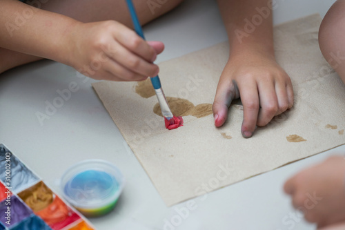 Kid hand do art activity with brush and slime coloring on paper