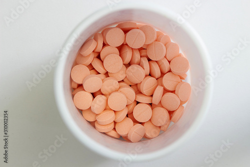 light orange tablets in white jar in medical healthcare drugstore concept,closed up