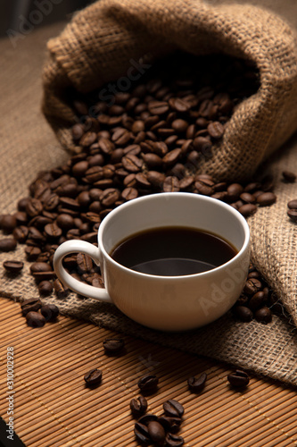 Coffee close-up. Coffee in a small white cup. Nearby is burlap and delicious coffee beans