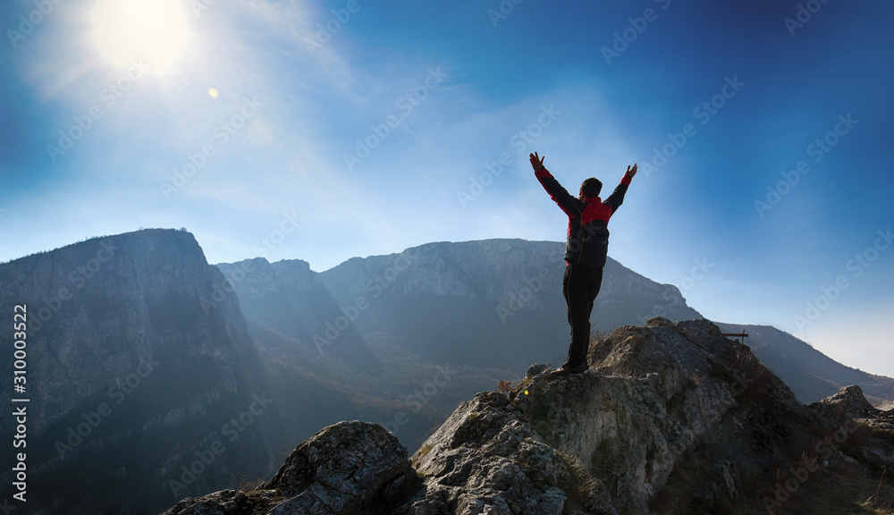 Adventurous man is standing on top of the mountain and enjoying the beautiful view. A man stands on the edge of a cliff in Sicevo Gorge, Serbia. Travel Lifestyle emotional concept