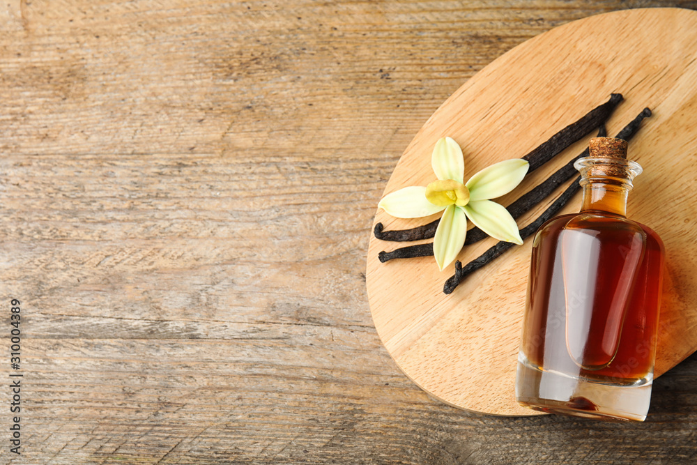 Flat lay composition with vanilla extract on wooden table. Space for text Flat lay composition with vanilla extract on wooden table. Space for text