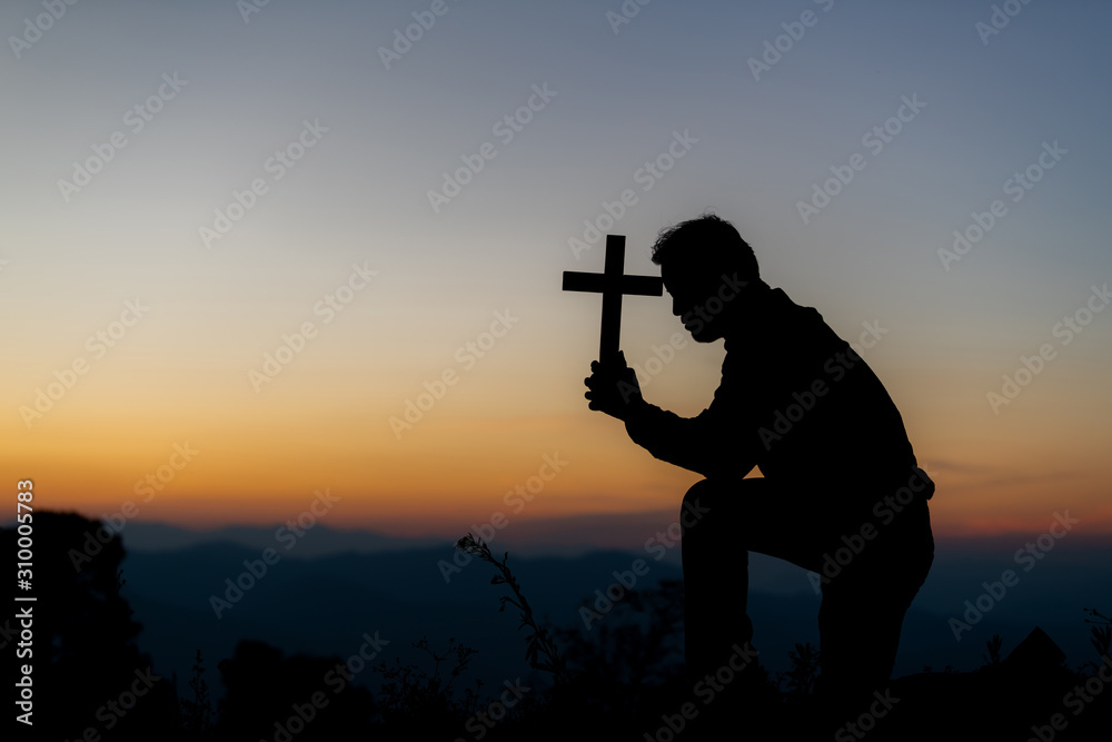 Silhouette of a young Christian praying to God at sunrise in the background of Christianity concept Silhouette of a young Christian praying to God at sunrise in the background of Christianity concept