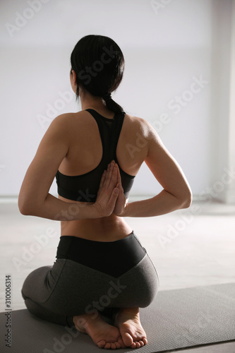 Young woman practicing seiza asana in yoga studio, back view. Vajrasana pose photo