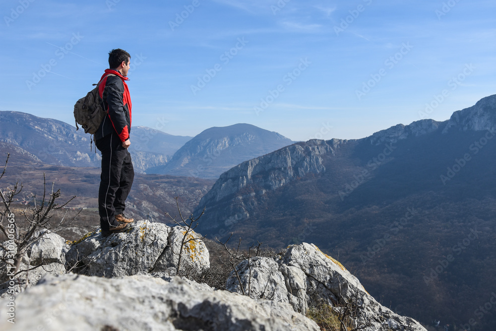 Adventurous man is standing on top of the mountain and enjoying the beautiful view. A man stands on the edge of a cliff in Sicevo Gorge, Serbia. Travel Lifestyle emotional concept