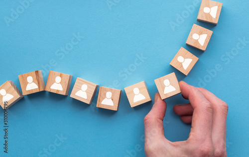 Hand choosing a wooden person block from a set. Employment choice concept photo