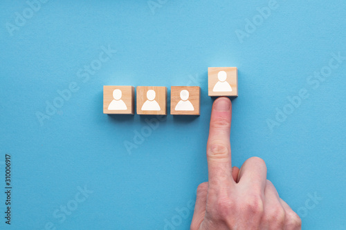 Hand choosing a wooden person block from a set. Employment choice concept photo