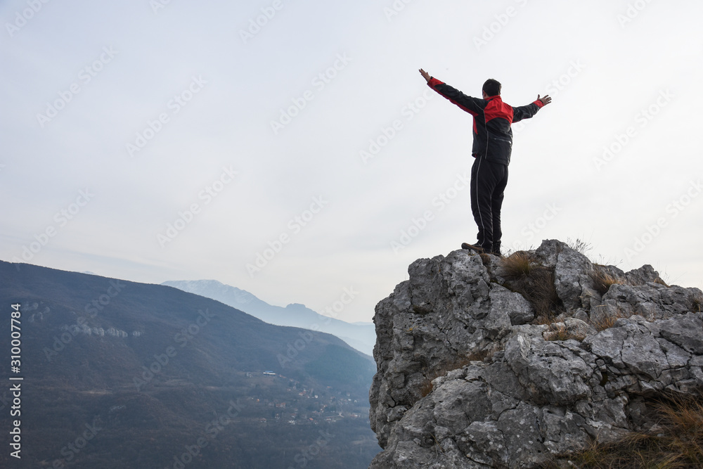 Adventurous man is standing on top of the mountain and enjoying the beautiful view. A man stands on the edge of a cliff in Sicevo Gorge, Serbia. Travel Lifestyle emotional concept