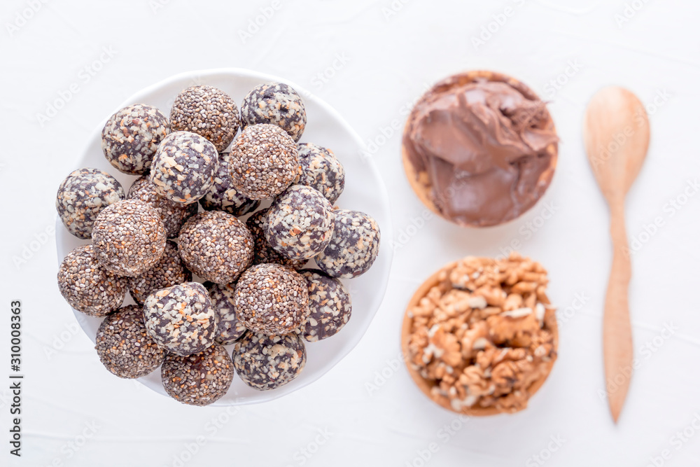 Natural healthy raw energy bites, chocolate paste and mix of dried fruits with nuts on a white table. Top view Natural healthy raw energy bites, chocolate paste and mix of dried fruits with nuts on a white table. Top view