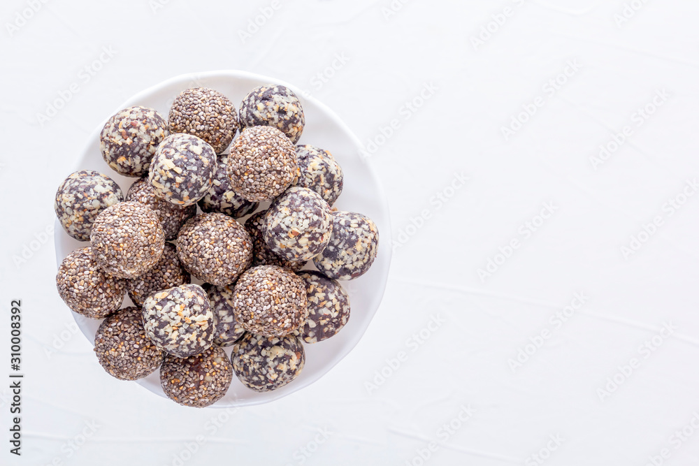 Healthy organic energy bites with nuts, cacao, banana and honey - sports food, vegetarian raw protein snack on a white table. Copy space. Top view Healthy organic energy bites with nuts, cacao, banana and honey - sports food, vegetarian raw protein snack on a white table. Copy space. Top view