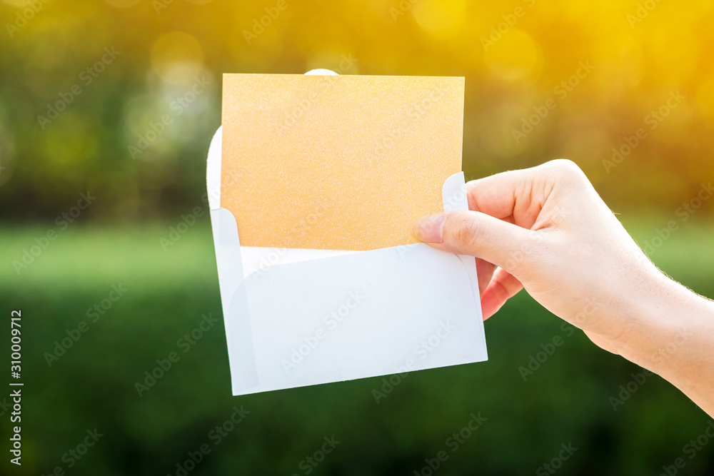 Woman hand giving a gift voucher or a business cards to customer or partners on bokeh background in the public park, For shopping or Introduce yourself concept. Woman hand giving a gift voucher or a business cards to customer or partners on bokeh background in the public park, For shopping or Introduce yourself concept.