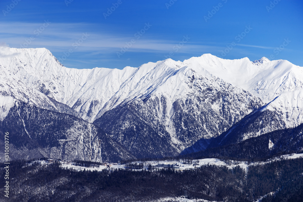 Panoramic view of winter peaks of mountains covered snow. Natural landscapes with Caucasus mountain. Rosa Khotor ski resort.
