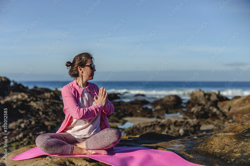 Brunette woman practicing yoga on the beach
