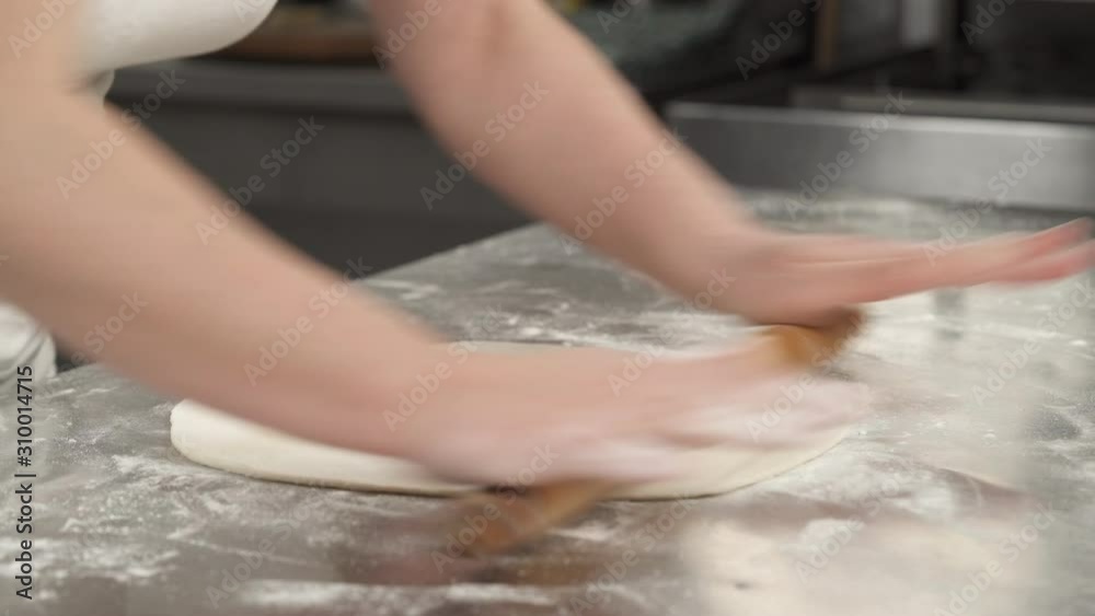 The chef is rolling out the dough with the rolling pin in the restaurant kitchen. Pastry making concept The chef is rolling out the dough with the rolling pin in the restaurant kitchen. Pastry making concept