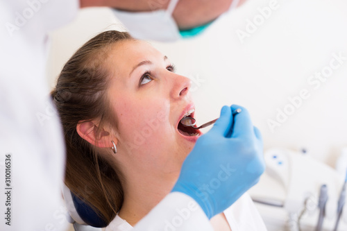 Dentist in white is taking examination of a young female