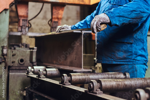 Worker is controlling a process of rail cutting at busy metal factory. photo