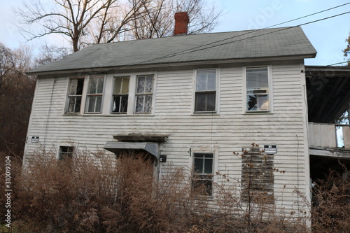 old historic abandoned New England house with broken windows and peeling paint