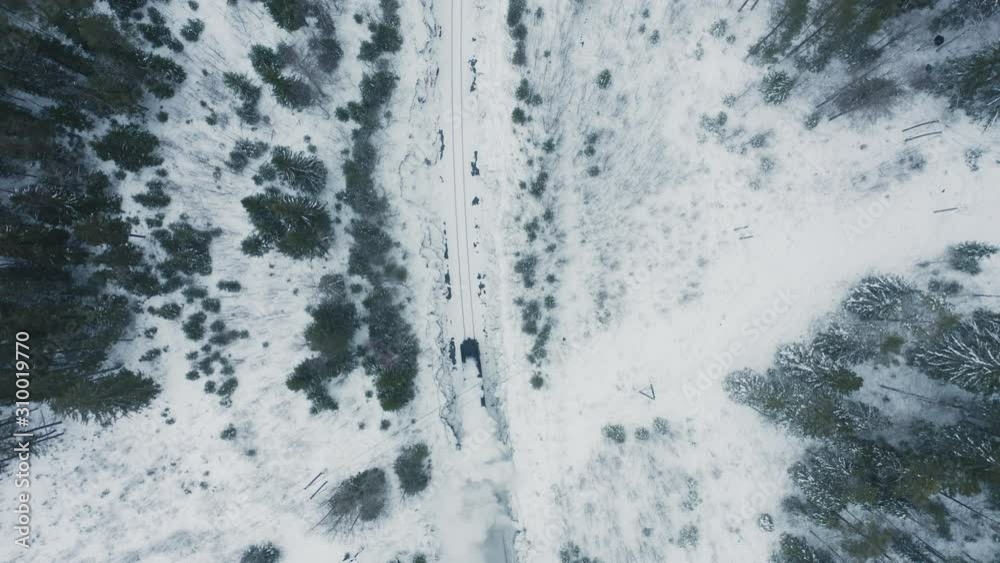 Aerial top view old retro steam train running in snow covered forest. Winter christmas season. Snow covered pine and spruce around railway