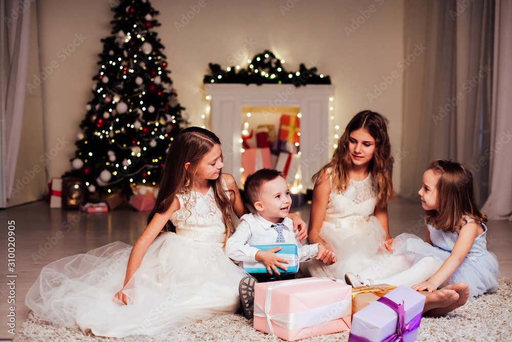 the little boy and three girls open Gifts Christmas new year tree Garland the little boy and three girls open Gifts Christmas new year tree Garland