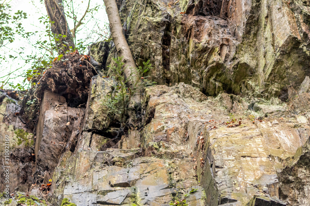 Massive Felswand aus Schiefergestein mit Felsvorsprüngen, grünem Moos, schroffen Kanten und steilen Klippen zeigt ein Kletterparadies für Free Climbing, Kletterer und Wanderer durch felsiges Gebirge