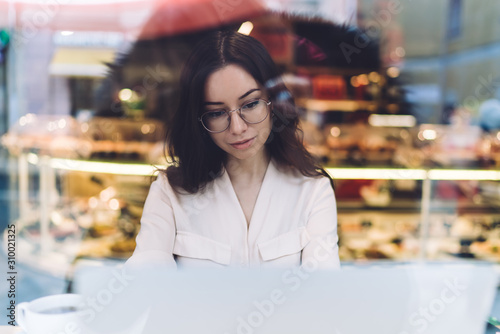 Young woman sitting in cafe with laptop and coffee