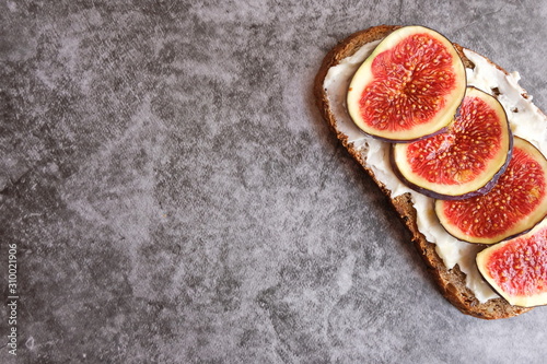 One sandwich with figs, cheese, honey and nuts on a gray background. Homemade. Casual autumn kitchen. The concept of healthy eating. Copy space.
