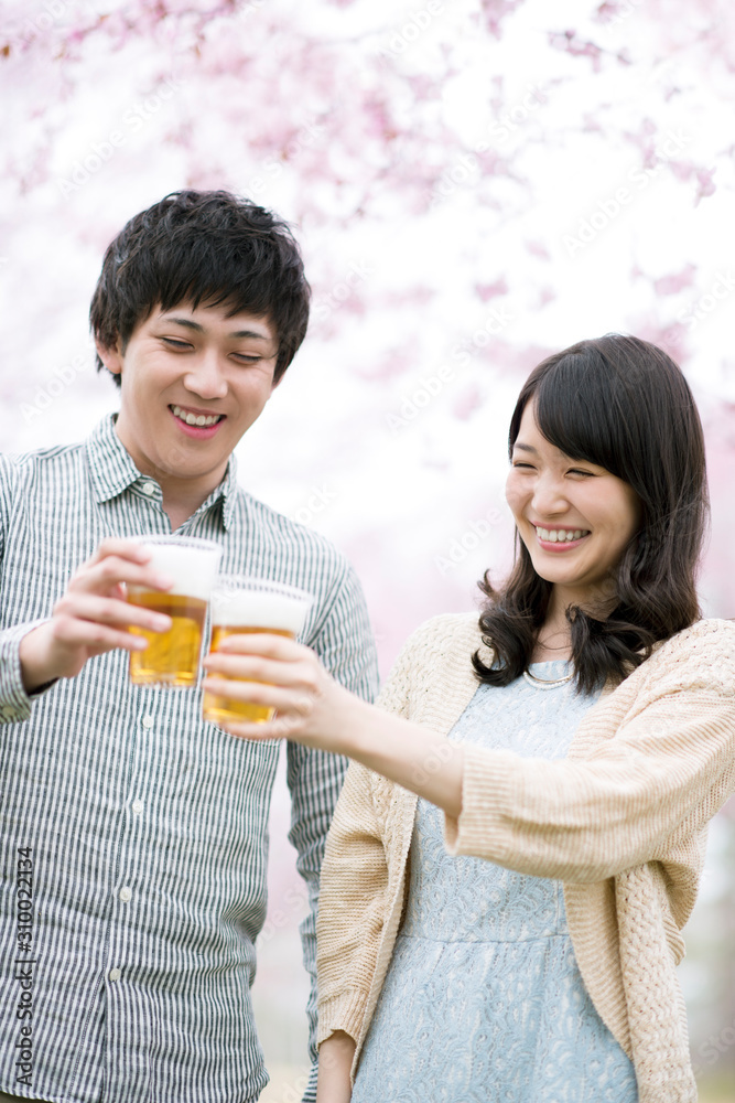 桜の前で乾杯をするカップル