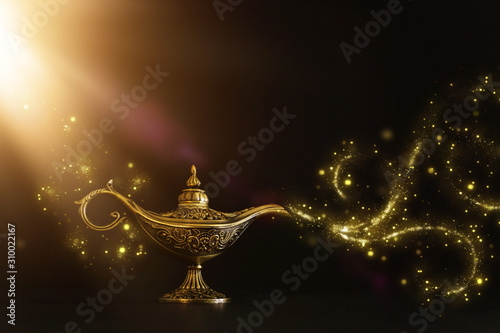 Image of magical mysterious aladdin lamp with glitter sparkle smoke over black background. Lamp of wishes