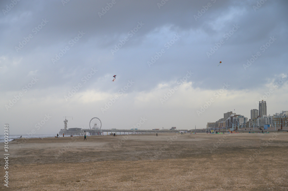 Scheveningen skyline seen from the beach, with the buildings on the pedestrian promenade and the pier. A few kites in the sky. Scheveningen skyline seen from the beach, with the buildings on the pedestrian promenade and the pier. A few kites in the sky.
