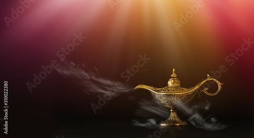 Image of magical mysterious aladdin lamp with glitter sparkle smoke over black background. Lamp of wishes photo