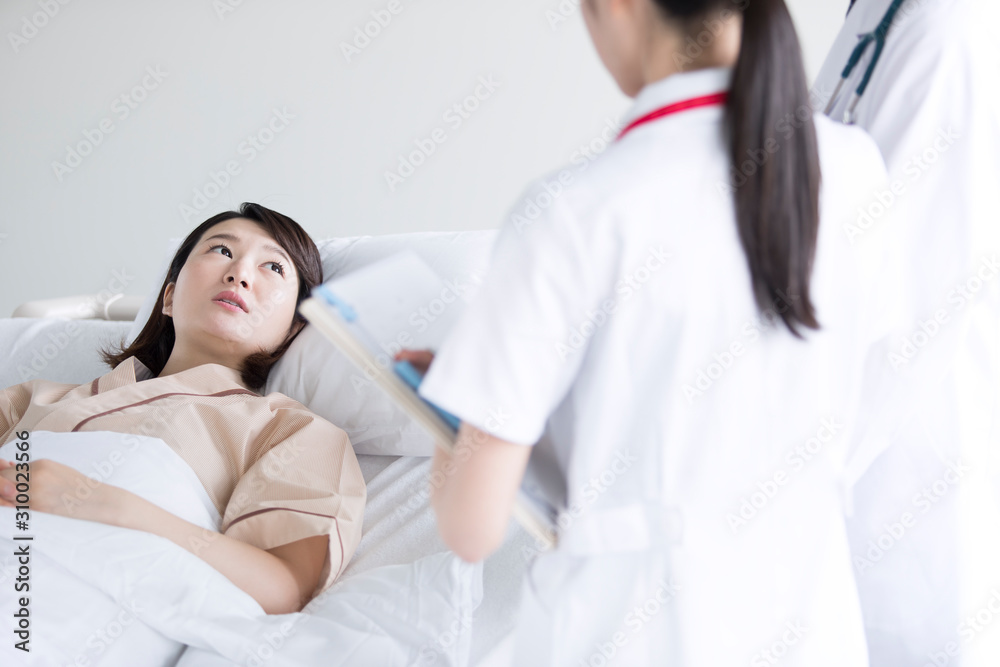 ベッドで医師の診察を受ける女性入院患者 ベッドで医師の診察を受ける女性入院患者