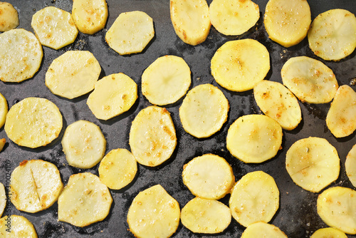 Potatoes sliced to thin circles  seasoned with spices  grilled on electric grill  view from above