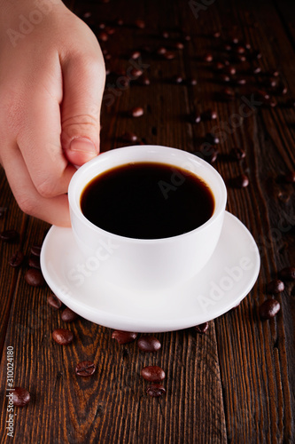 Woman Hand Raising A Cup Of Coffee From Wooden Table