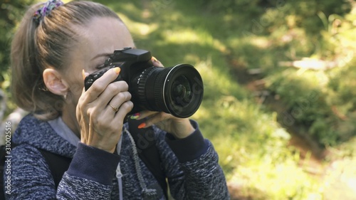 Traveler photographing scenic view in forest. One caucasian woman shooting close up look. Girl take photo video on dslr mirrorless camera. Professional photographer travel with backpack. Outdoor.