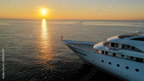 Aerial drone photo of luxury yacht docked in Aegean deep blue sea at sunset with beautiful golden colours, Greece © aerial-drone