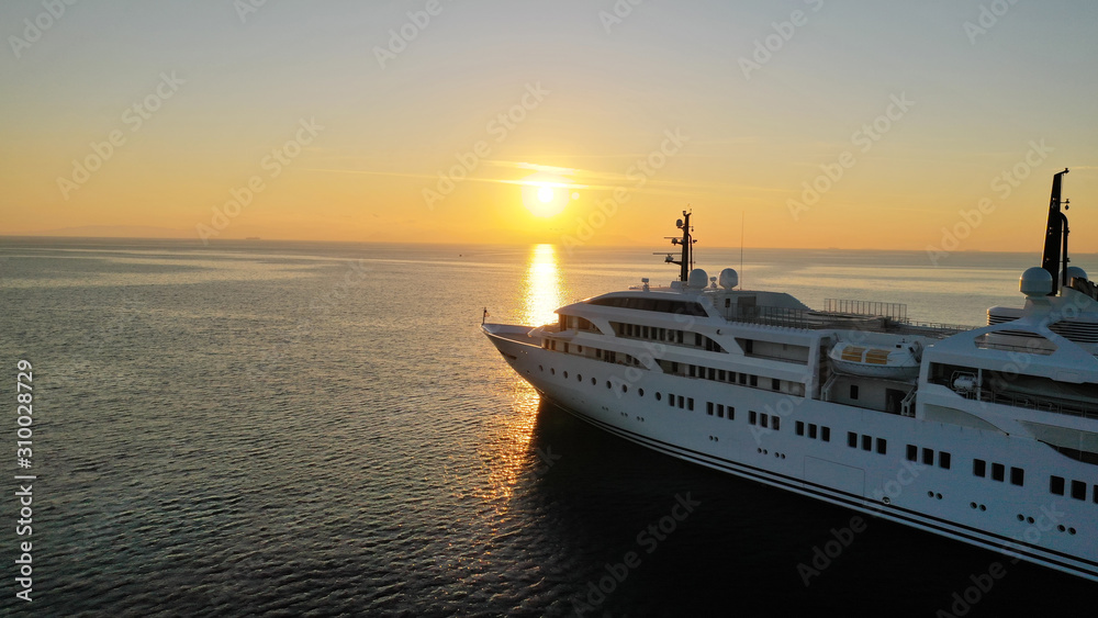 Aerial drone photo of luxury yacht docked in Aegean deep blue sea at sunset with beautiful golden colours, Greece