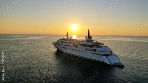 Aerial drone photo of luxury yacht docked in Aegean deep blue sea at sunset with beautiful golden colours, Greece © aerial-drone