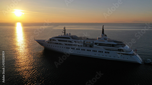 Fototapeta Naklejka Na Ścianę i Meble -  Aerial drone photo of luxury yacht docked in Aegean deep blue sea at sunset with beautiful golden colours, Greece