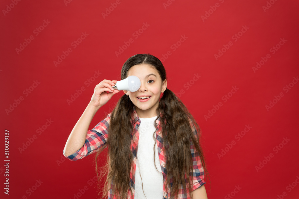 Fototapeta premium girl of success. cheerful child girl. little child hold light idea bulb. education concept. small school kid red background. small girl lightbulb. energy and electricity. creating a great idea