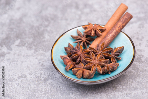 Star abise and cinnamon in a blue bowl on a grey structured background